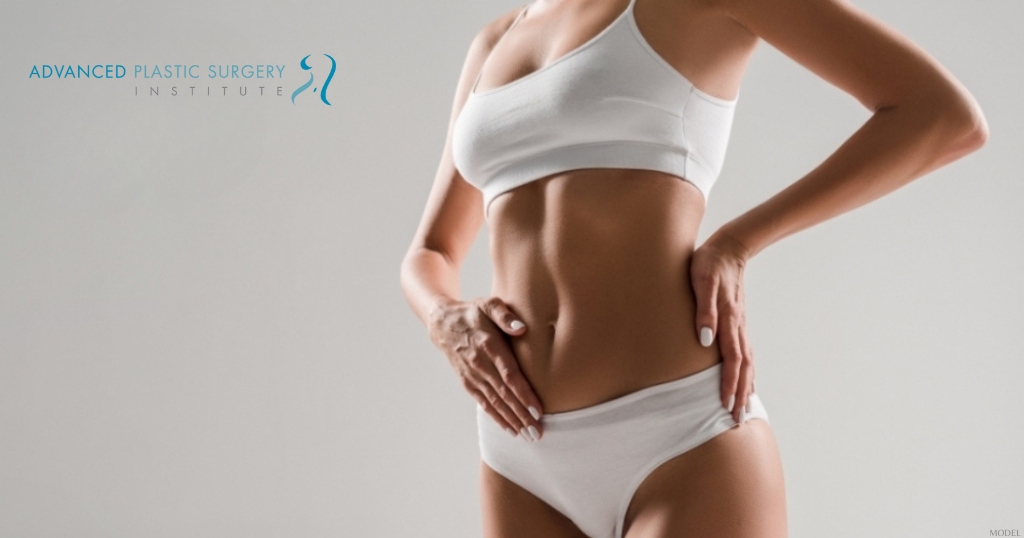 Woman resting her hands on her abdomen to highlight tummy tuck results. (model)
