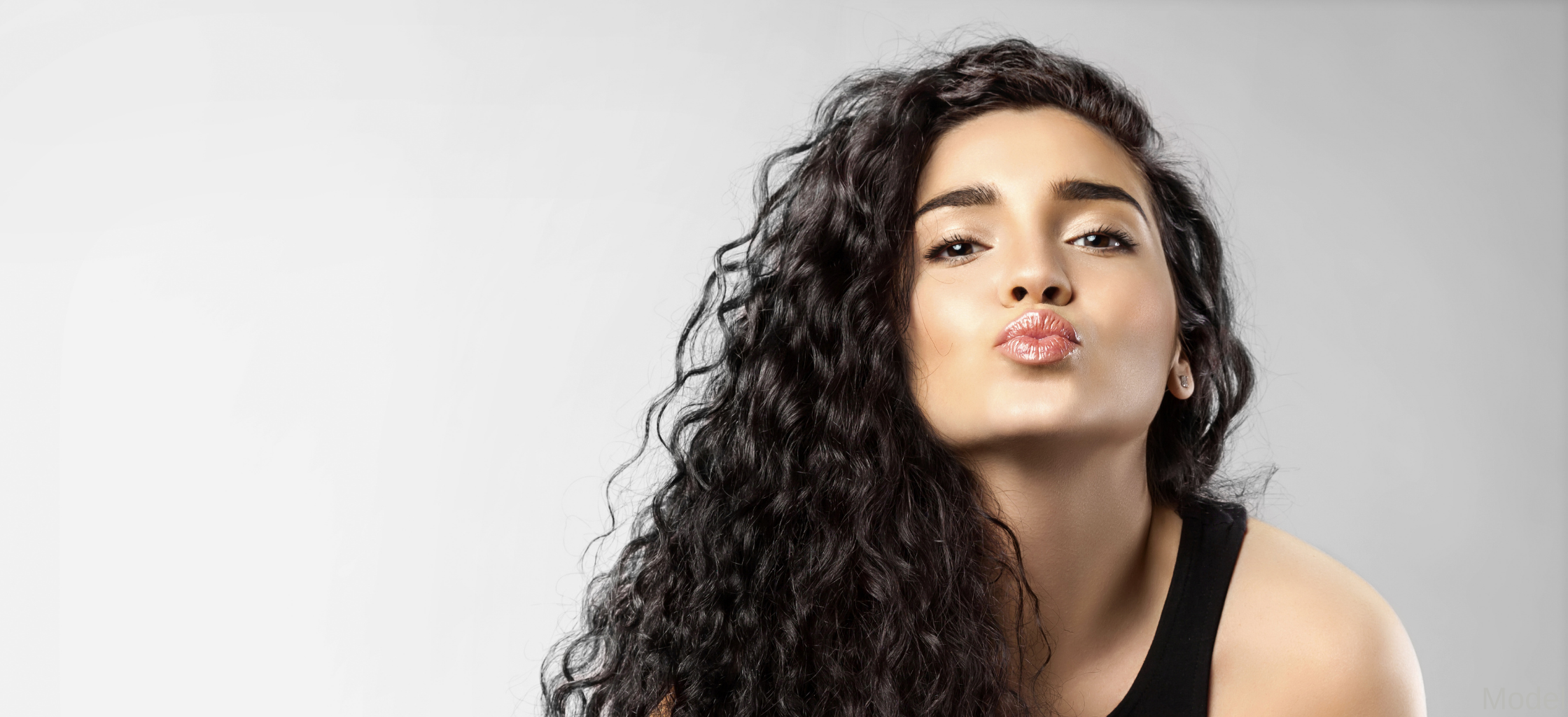 woman with curly hair makes kissing face