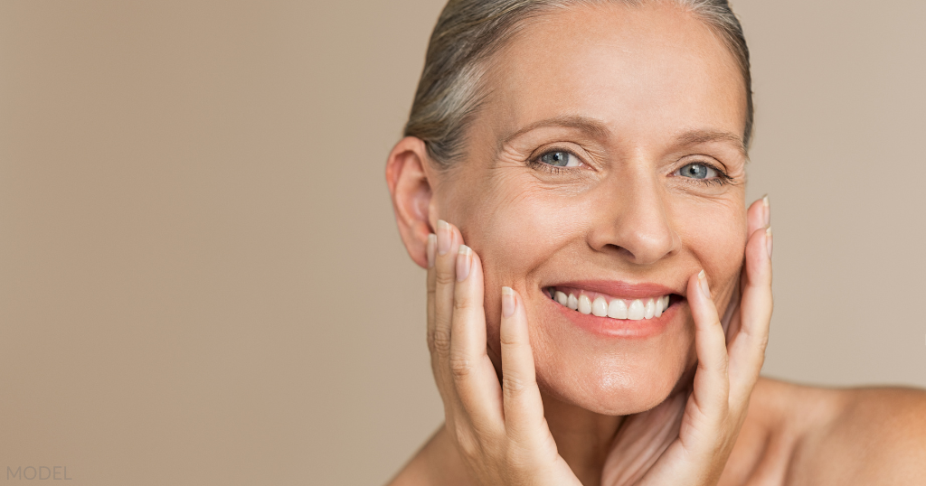 Older woman smiling with her hands on her face (model)