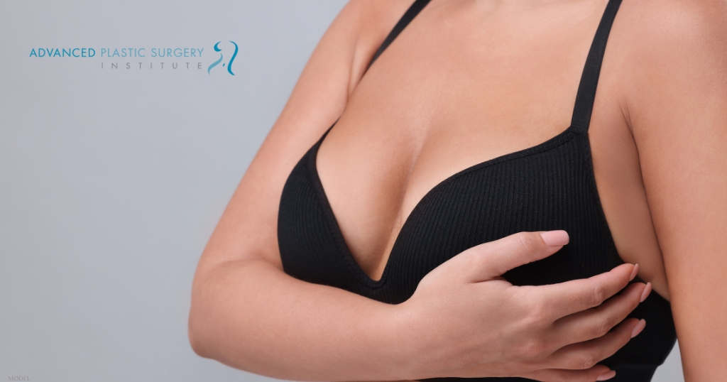 a person in a black bra top with their hands on their chest (model)