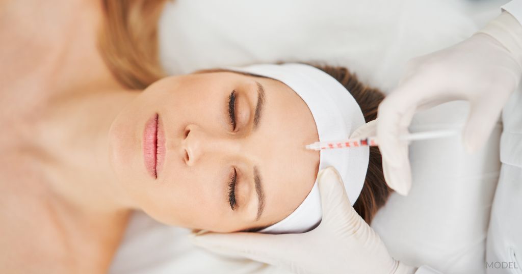 Relaxed looking woman laying down while receiving Botox injections on her forehead (MODEL).