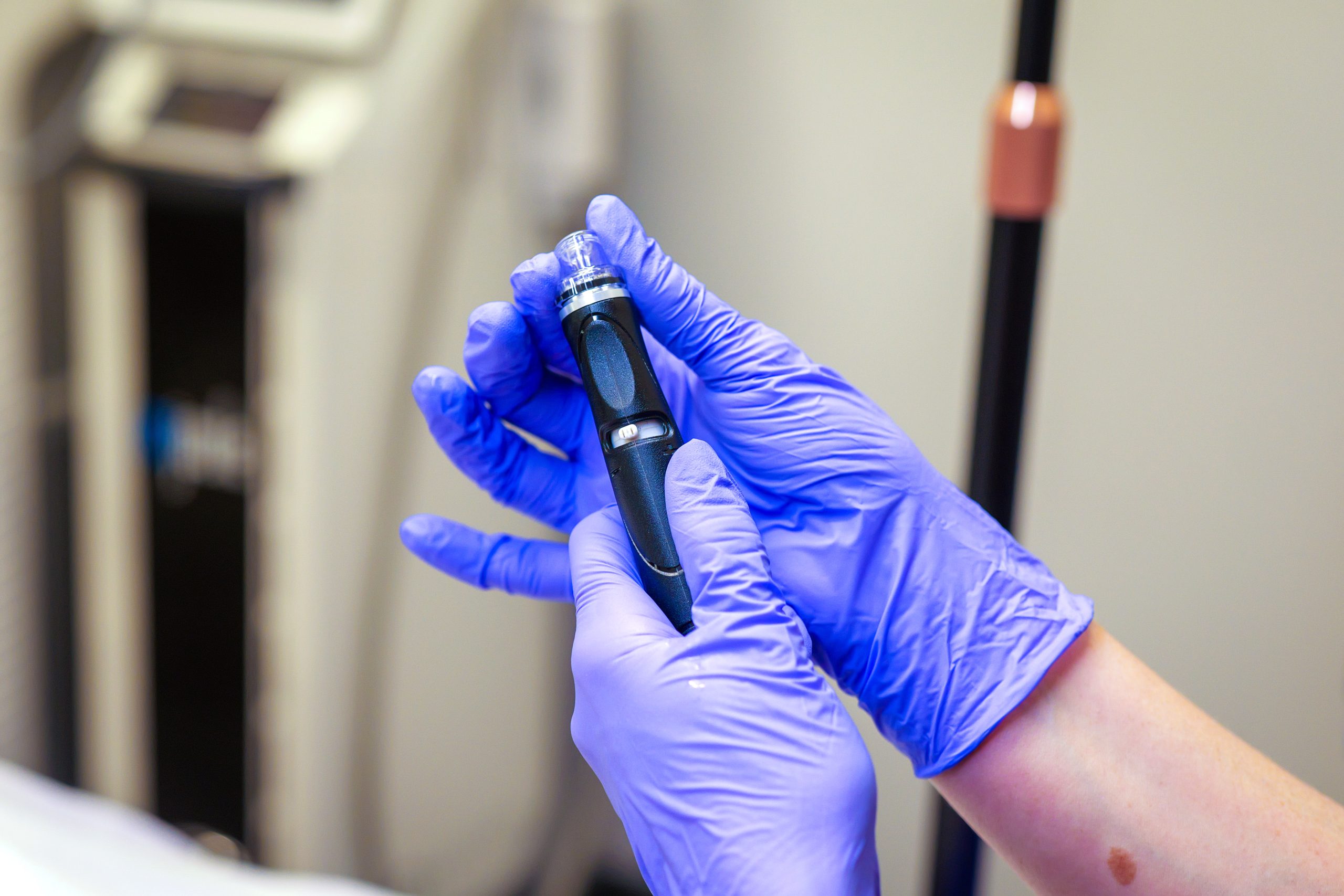 Surgical covered hands hold a microneedling pen